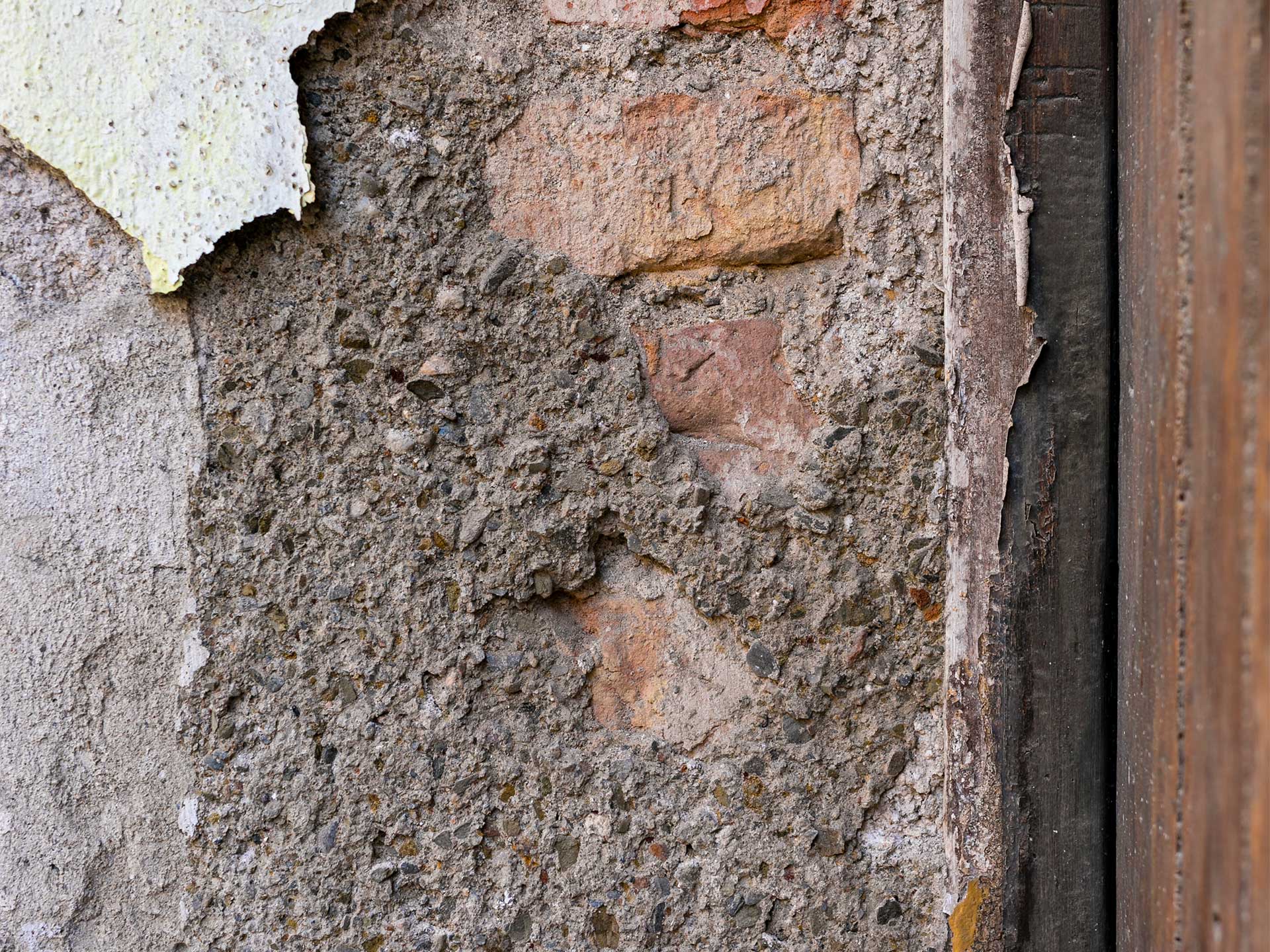 A wall with a hole showing a piece of paper, indicating asbestos removal work in progress.
