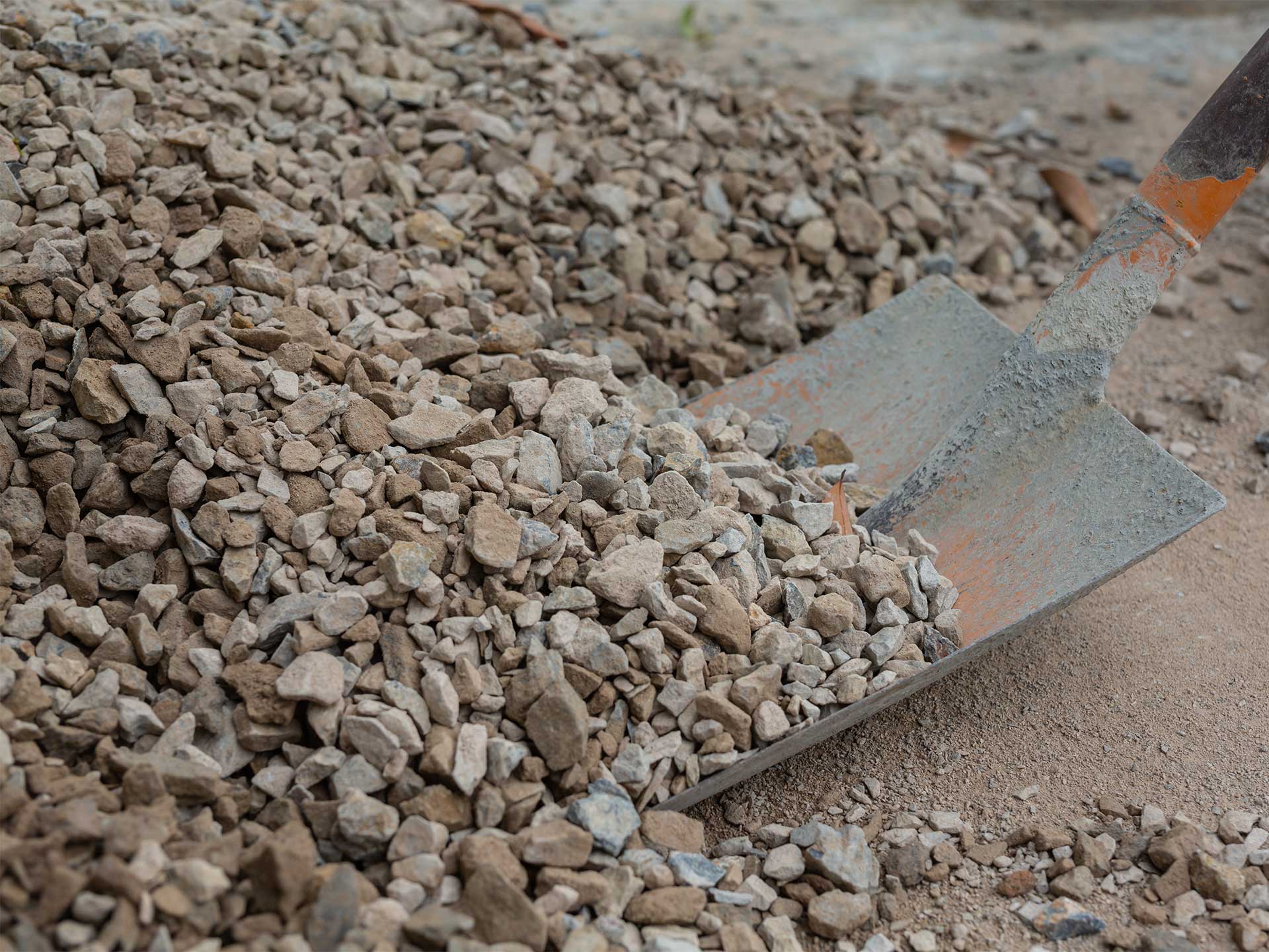 A shovel spreads gravel on the ground as part of land remediation efforts.