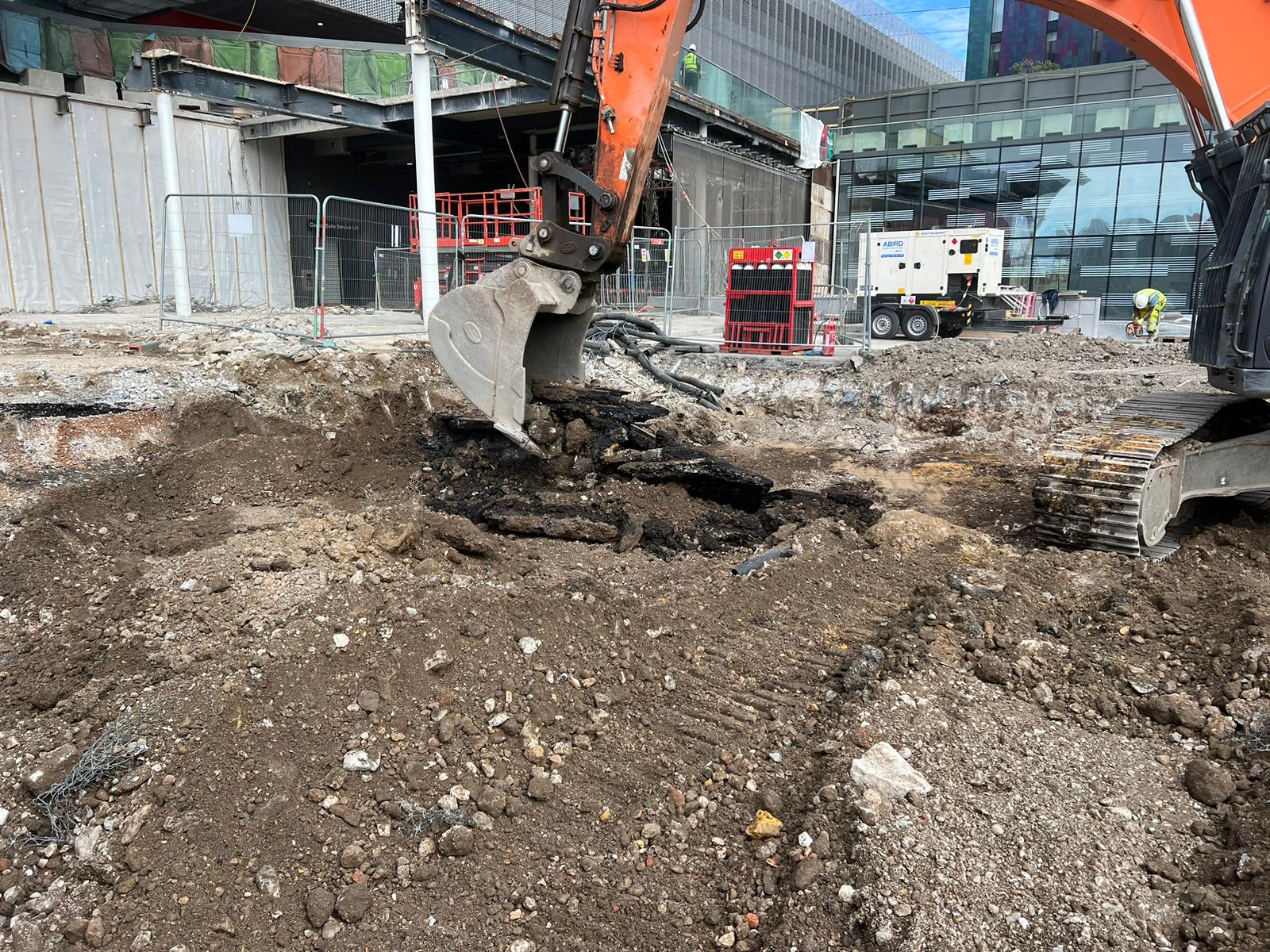 A construction worker digging a hole in the dirt as part of enabling works for a new project.